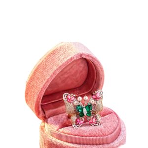 Butterfly-shaped ring with green center stone, pink gemstone accents, pearls and diamond detailing set in rose gold.