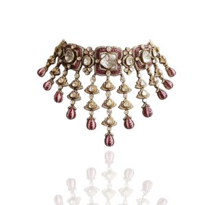 Structured polki and ruby choker necklace with hanging drops by Akoya Jewels displayed on a light mannequin with greenery background.