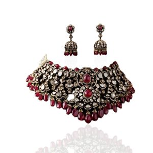 Rich polki choker with ruby accents and matching earrings by Arunbhai Maneklal Jhaveri and Sons on a green mannequin.
