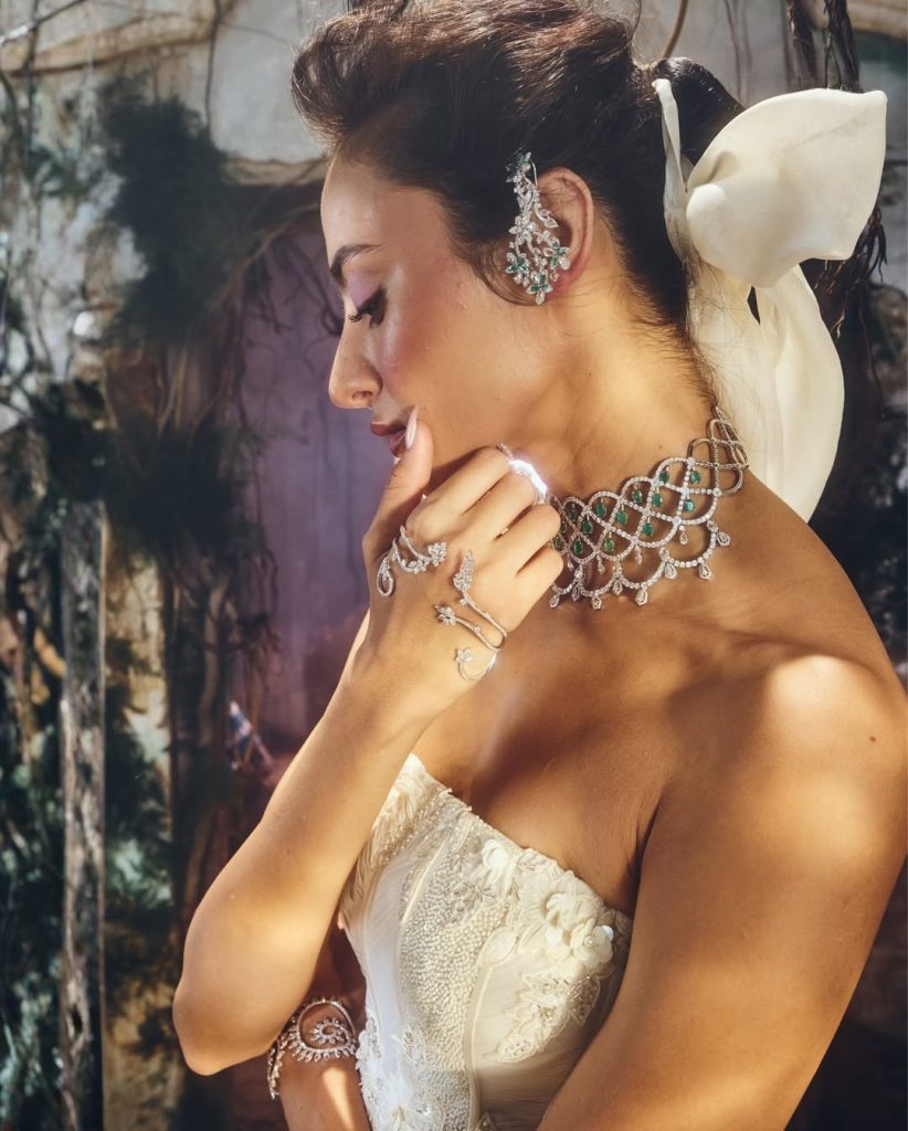 Bride in ivory corset gown wearing sculpted diamond choker with emerald accents. 