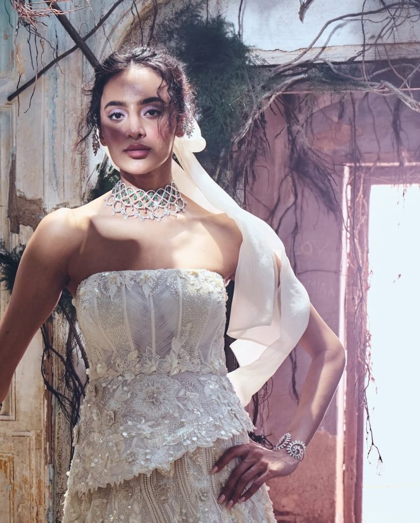 Bride in ivory corset gown wearing sculpted diamond choker with emerald accents. 