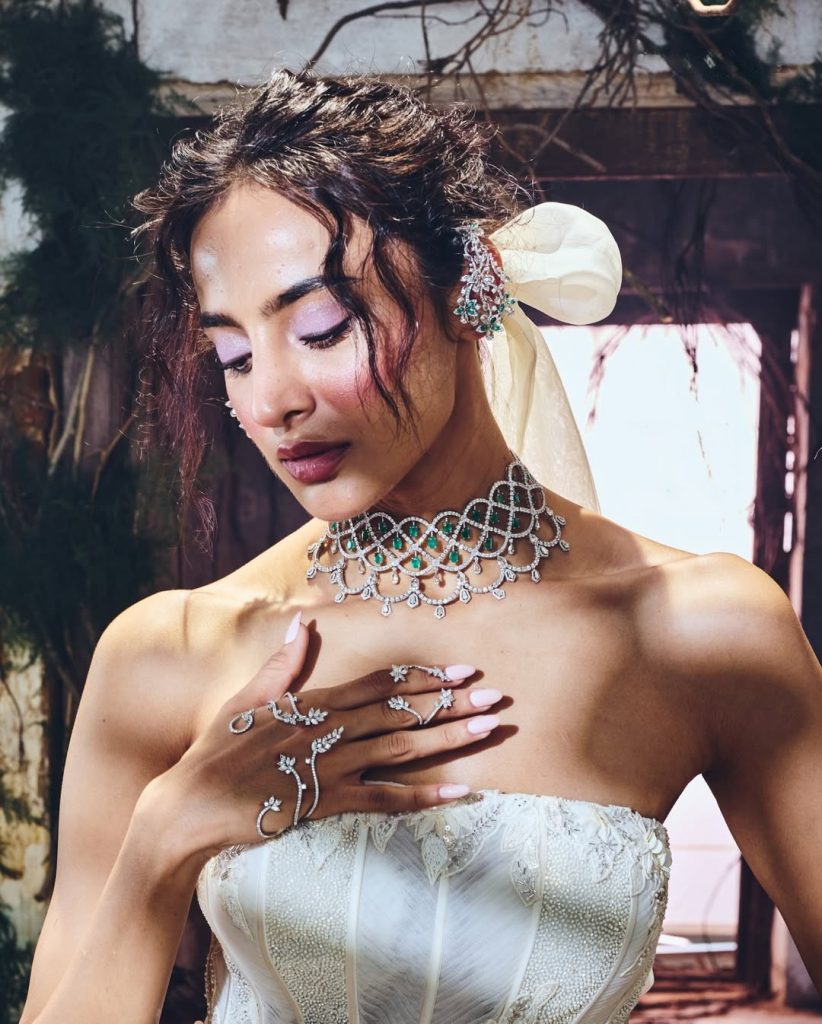 Bride in ivory corset gown wearing sculpted diamond choker with emerald accents. 