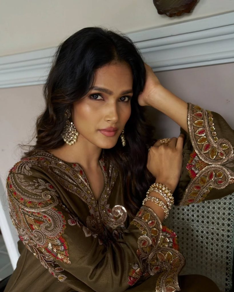 Bride in olive embroidered outfit wearing polki chandelier earrings and pearl accents. 