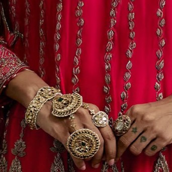 Bride in red ensemble wearing kundan polki choker with emerald and pearl drops. 