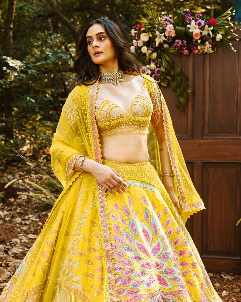 Bride in yellow lehenga wearing delicate diamond choker with soft green accents. 