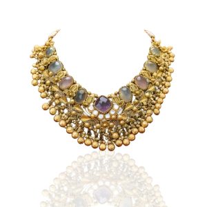 Gold necklace with subtle gemstone detailing displayed on red velvet bust