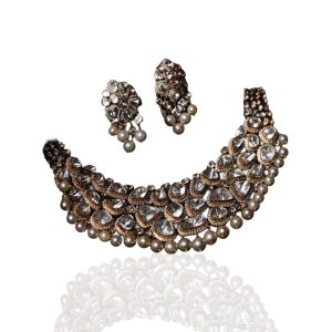 Bold uncut polki choker necklace with pearl edging by Harshiamlal Shiamlal Jewellers on dark blue fabric.