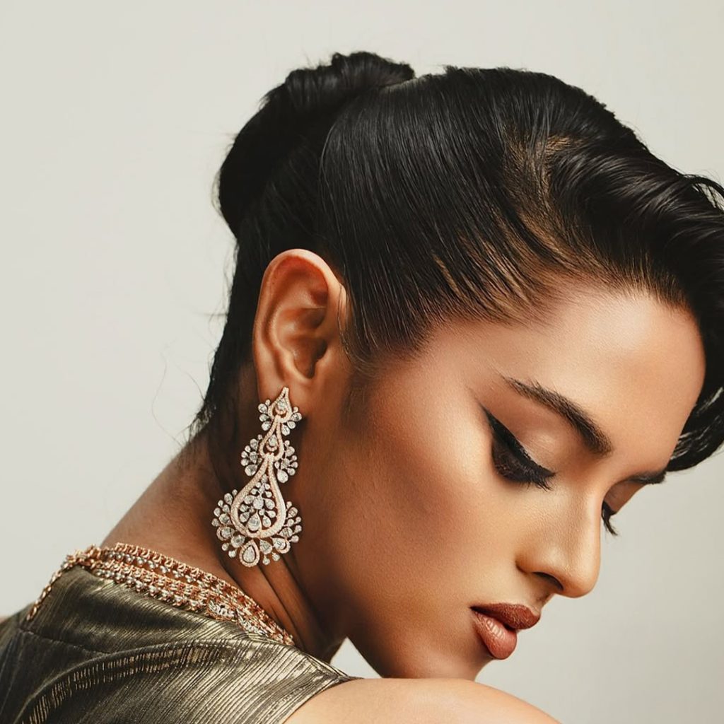 Model in metallic gown wearing intricate diamond choker and statement earrings. 