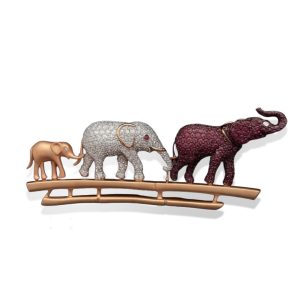 Ruby and diamond elephant brooch by Punjabi Saraf featuring three sculpted elephants on a curved gold bar.
