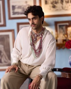 Male model wearing layered polki, diamond and emerald choker with gemstone strands styled over a white shirt.