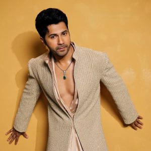 Varun Dhawan wearing a green gemstone pendant necklace styled with a textured outfit featuring jewellery by Akoya Jewels.