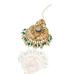 Close up of gold kundan maang tikka by Jagdish Jewels featuring uncut diamonds, emerald bead border, ruby accents and structured pearl fringe.