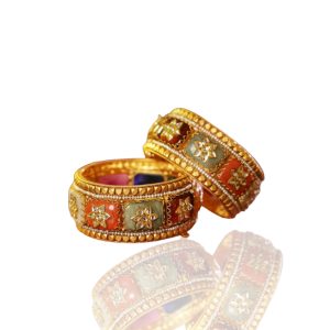 Pair of gold bangles with colourful enamel floral motifs by Punjab Jewels displayed on warm toned blocks.