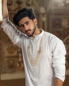 Male model in white kurta wearing layered pearl mala necklace by Rakesh Jewellers.