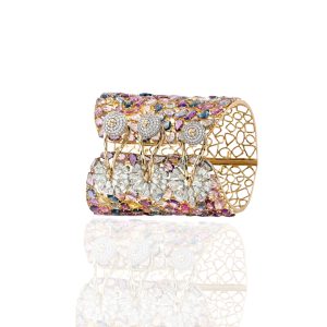 Wide gold cuff with pink blue and white gemstones by Sawansukha Jewellers on a white background.