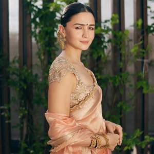 Alia Bhatt wearing traditional gold jhumka earrings by Khurana Jewellery House with a peach saree.