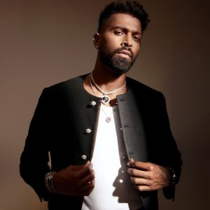 Hardik Pandya wearing layered gemstone necklaces styled with a black jacket and white shirt featuring jewellery by Mahesh Notandass.