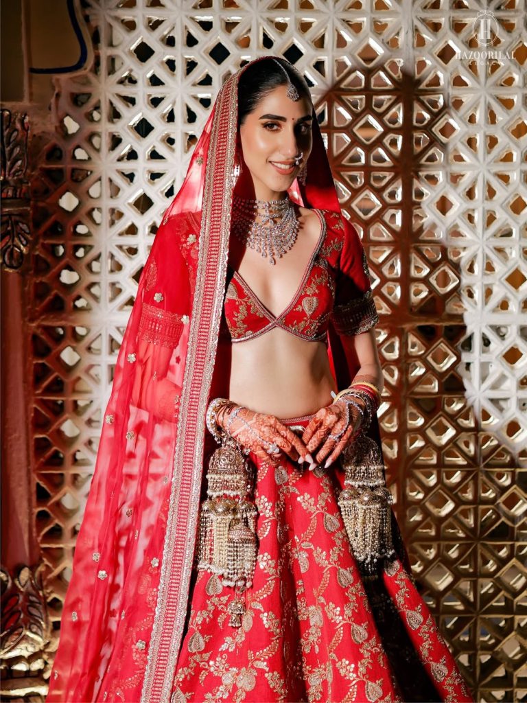 Bride in red bridal outfit with statement nath and detailed choker jewellery 
