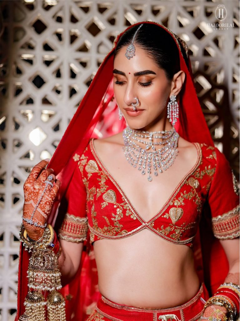Bride in red bridal outfit with statement nath and detailed choker jewellery 