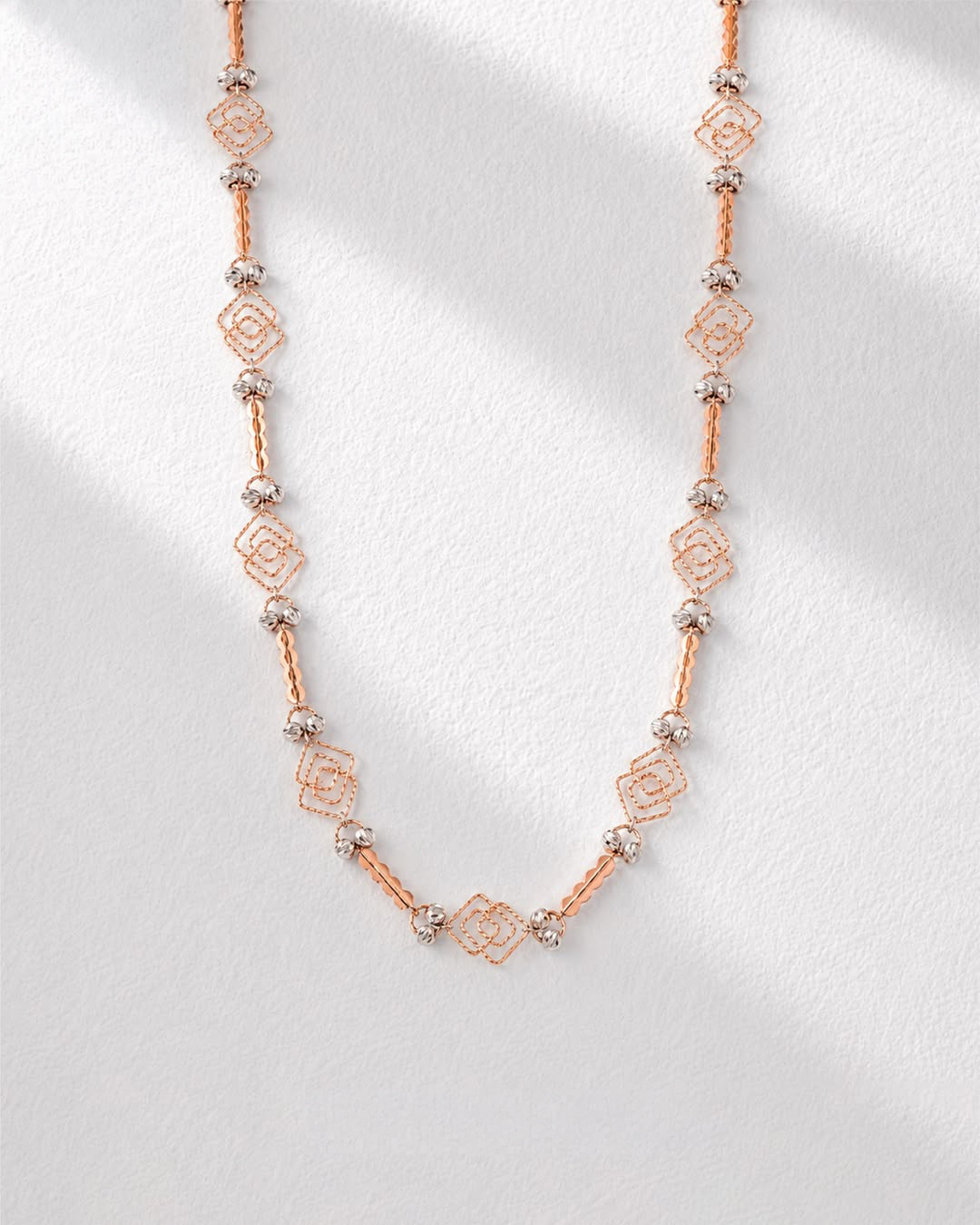 18KT rose gold geometric necklace with delicate bead accents and contemporary openwork design by Manubhai Jewels
