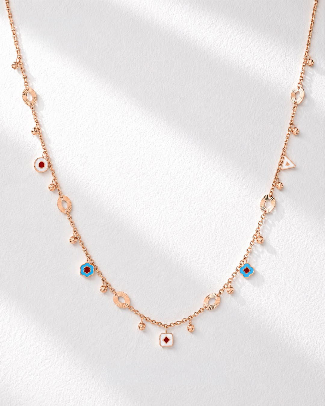18KT rose gold charm necklace with colourful enamel motifs and geometric details by Manubhai Jewels