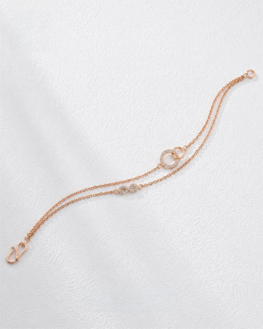 18KT rose gold double-chain bracelet with diamond-studded infinity motif by Manubhai Jewels