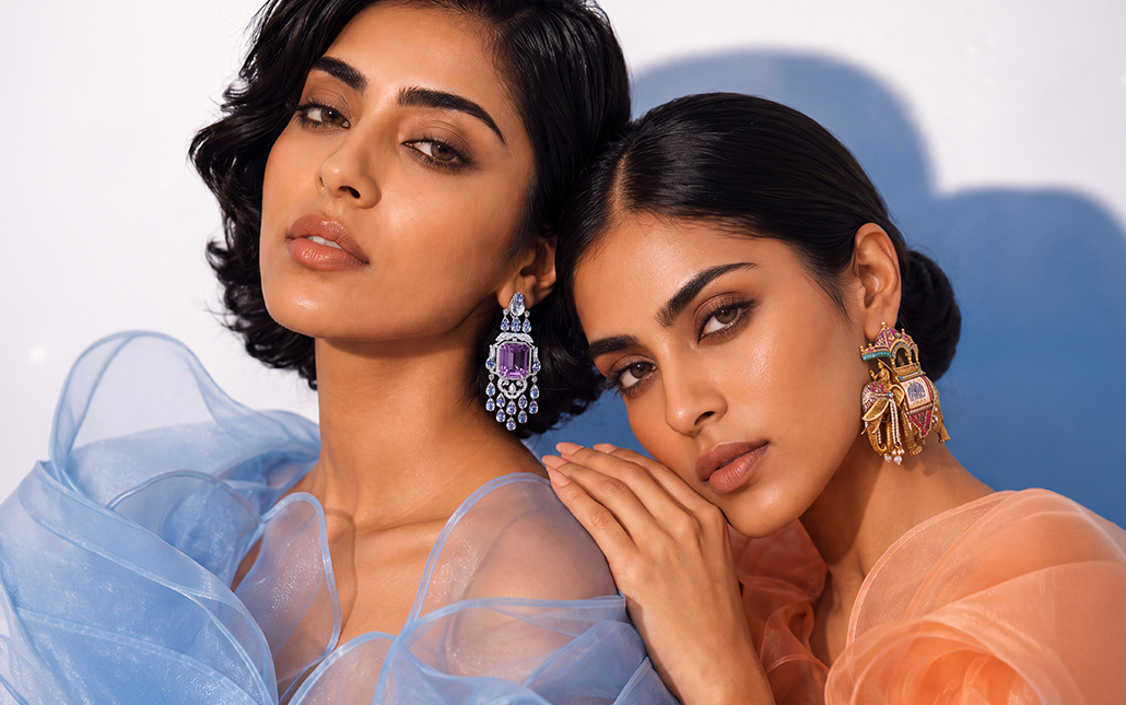 Two models wearing statement coloured gemstone earrings featuring purple gemstones and an ornate elephant-inspired design.