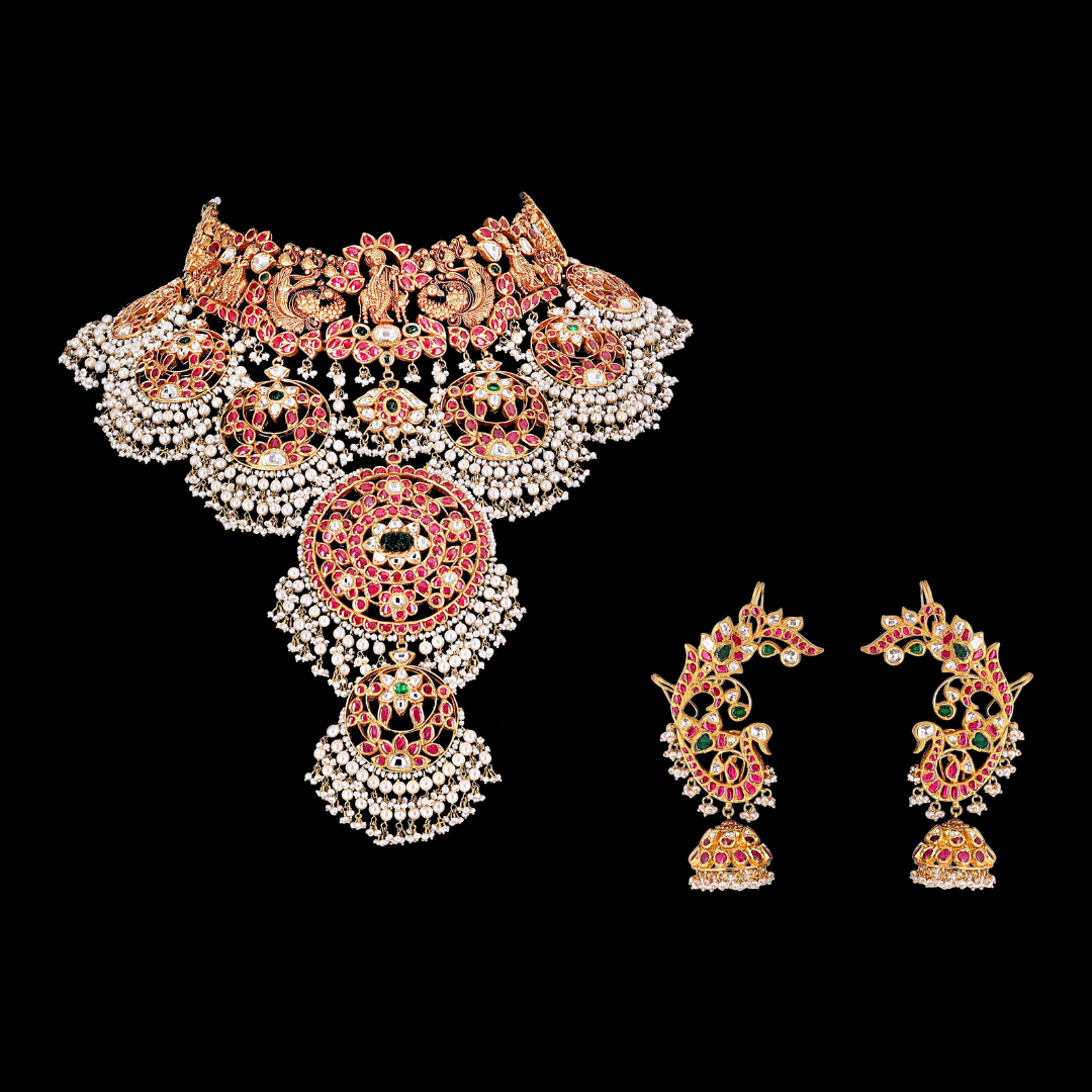 The Royal Palace antique studded gold bridal jewellery by PMJ Jewels featuring temple-inspired motifs and red, green and white stone detailing.