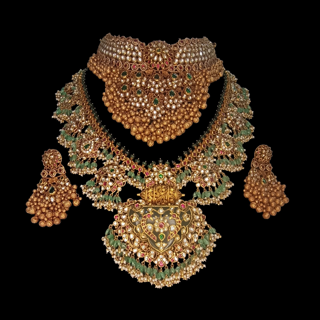 The Royal Guttapusalu antique studded gold bridal jewellery set by Sumeet Jewellers featuring pearl clusters, ornate pendant and green and red accents.