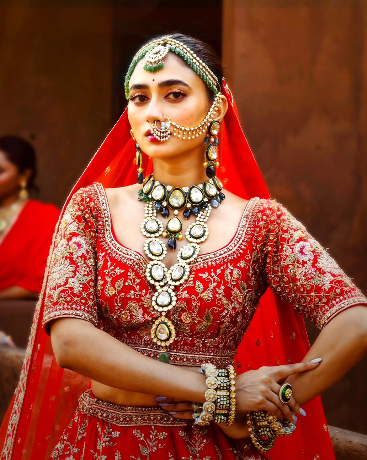 Bride wearing handcrafted Jadau and Kundan bridal jewellery by Sawansukha Jewellers with green gemstone necklace and statement earrings.