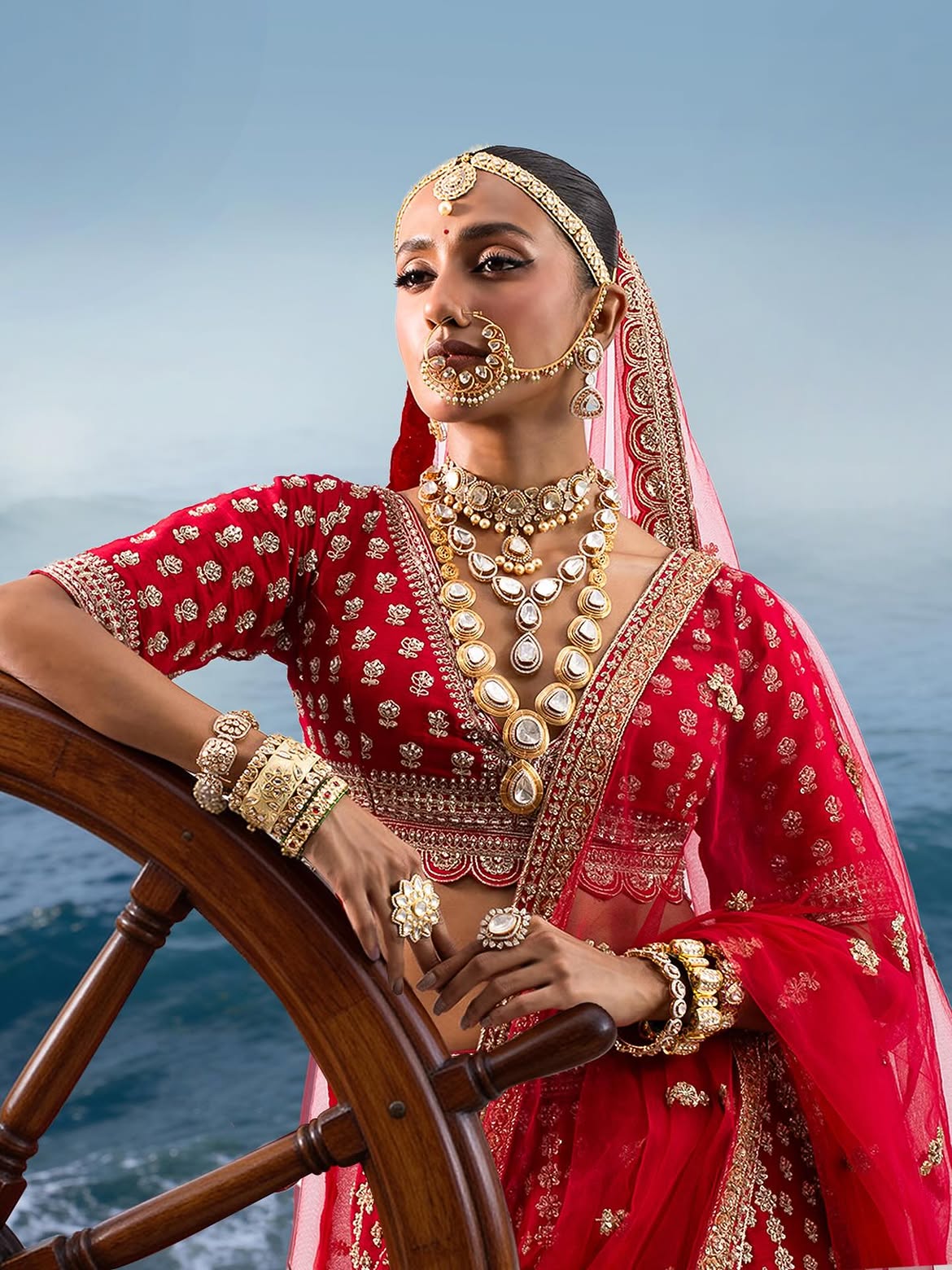 Bride wearing classic Polki bridal jewellery by Sawansukha Jewellers featuring layered necklaces, choker, maang tikka and bridal bangles.