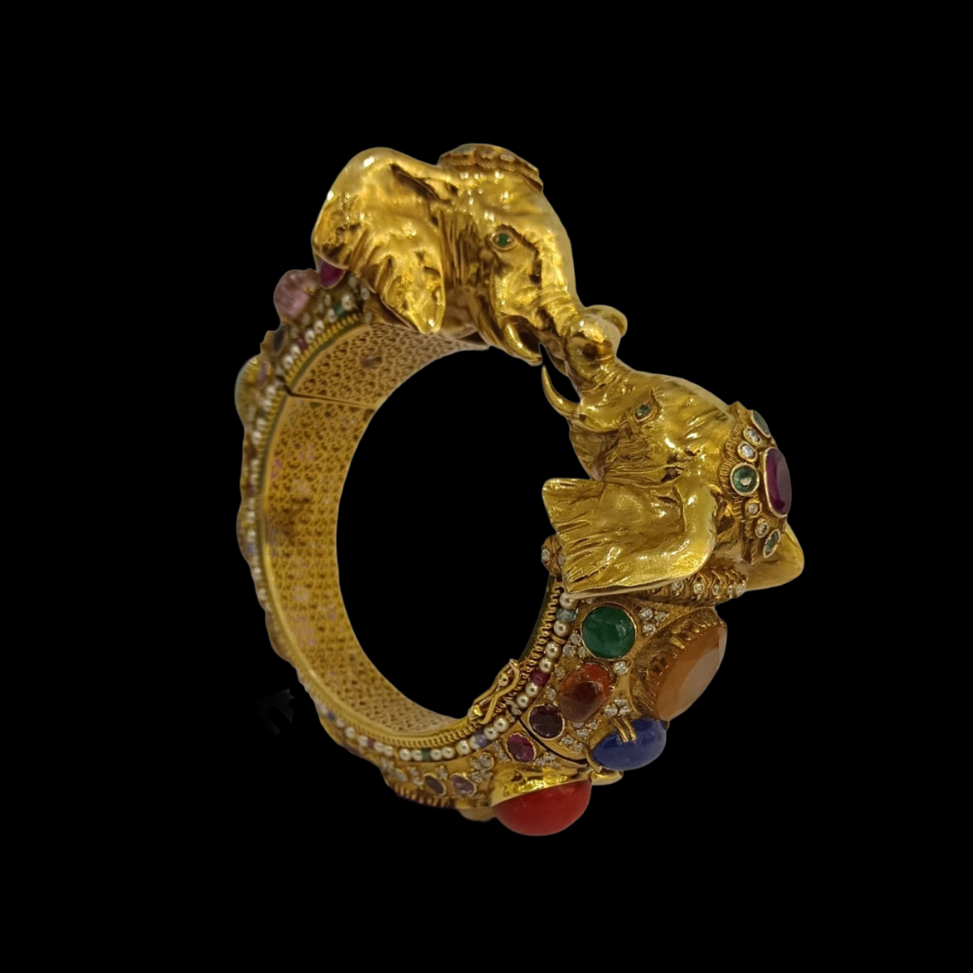 AJB Fine Jewels Gaja Bandhan studded gold bangle featuring sculpted guardian elephants and colourful gemstone detailing. 