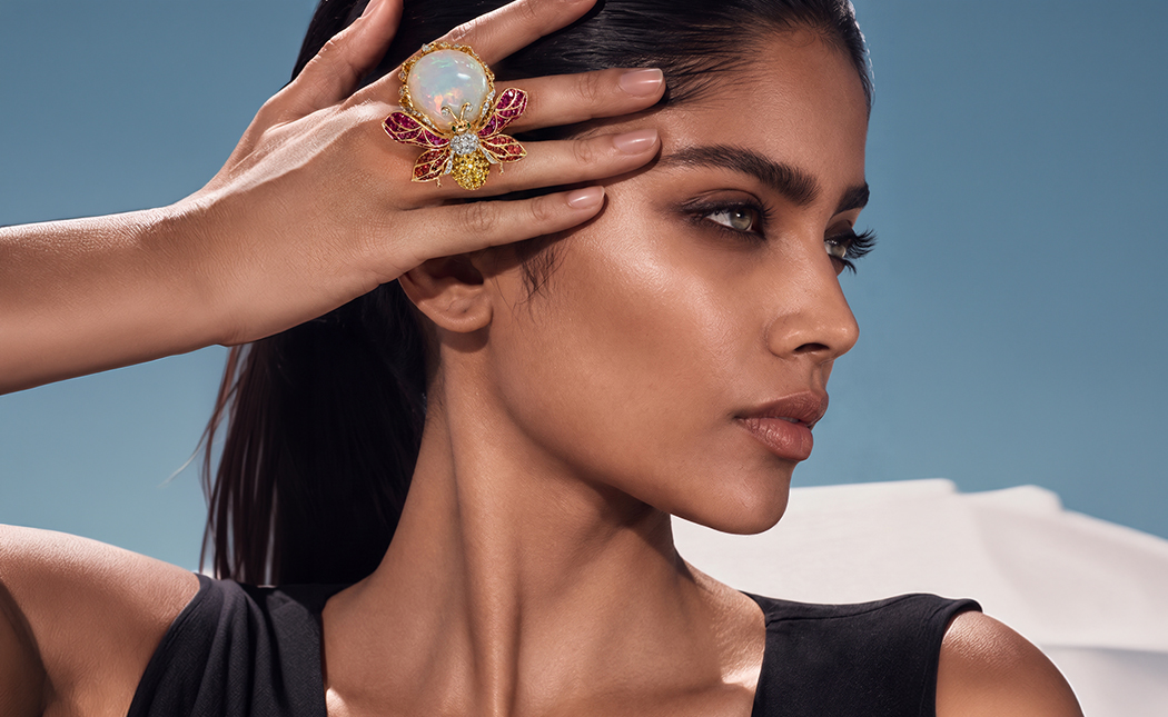 Model wearing Farah Khan Fine Jewellery’s The Nectar Keeper statement ring, featuring a bee and floral motif with an opalescent centre, ruby-toned details and diamonds.